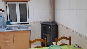 Un comedor con mantel verde, sillas de madera, un tazón de vidrio azul, una cocina con fregadero, armarios y estufa.