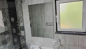 Un baño moderno con lavamanos, inodoro y ducha blancos.