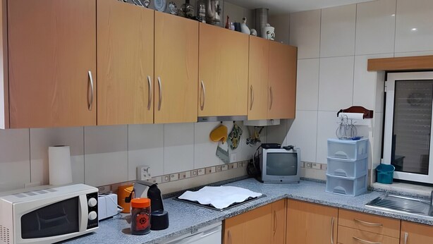 Una cocina compacta con lavadora, microondas y una pequeña encimera.