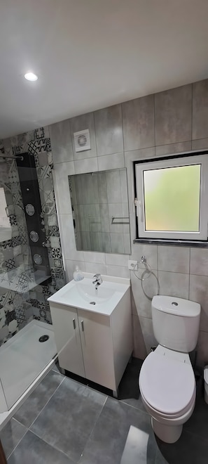 A modern bathroom with a white sink, toilet, and shower.