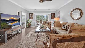 A living room with a television, sofa, coffee table, and decorative items.