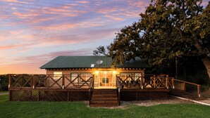 Een houten chalet met een groen dak, een terras en een overdekte veranda.