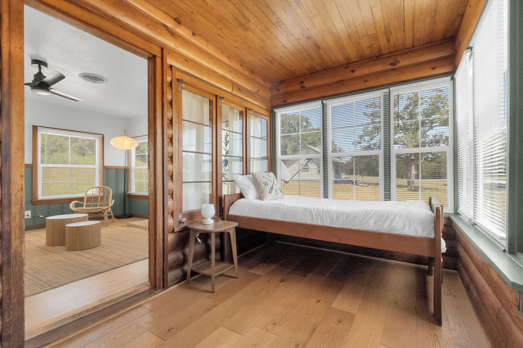 A wooden-framed room with a bed, a table, and a chair.