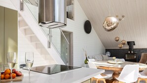 A modern kitchen with a white countertop, stainless steel appliances, and a wooden dining table with white chairs.