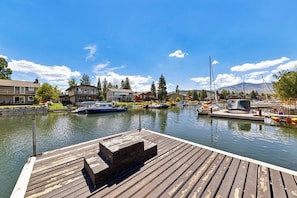 A wooden dock with boats, a marina, and residential buildings in the background.