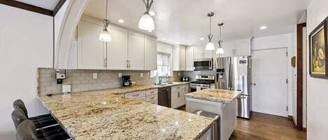 A modern kitchen with granite countertops, stainless steel appliances, and pendant lighting.