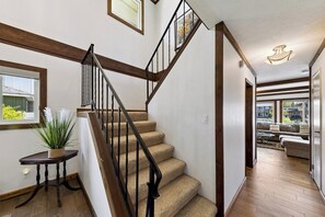 A staircase with a wooden handrail and black balusters, leading to a living area with a sofa and a view of the outdoors. - Waterfront Family Home with Private Boat Dock (South Lake Tahoe)