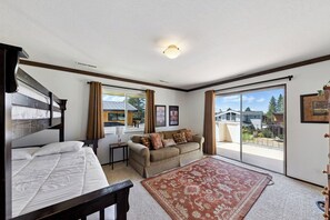 A bedroom with a bed, a sofa, a small table, and a view of the outside. - Waterfront Family Home with Private Boat Dock (South Lake Tahoe)