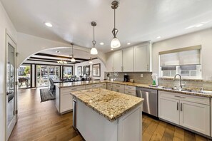 A modern kitchen with granite countertops, stainless steel appliances, and pendant lighting.