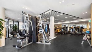 A modern gym with various exercise equipment, including weight machines and cardio machines. - Modern Style Comfortable 1Bedroom Apt with Parking (Phillip)