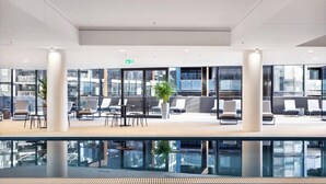 A modern indoor pool area with lounge seating and a glass barrier. - Modern Style Comfortable 1Bedroom Apt with Parking (Phillip)
