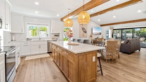 Una cocina moderna con armarios blancos, una isla de madera e iluminación colgante.