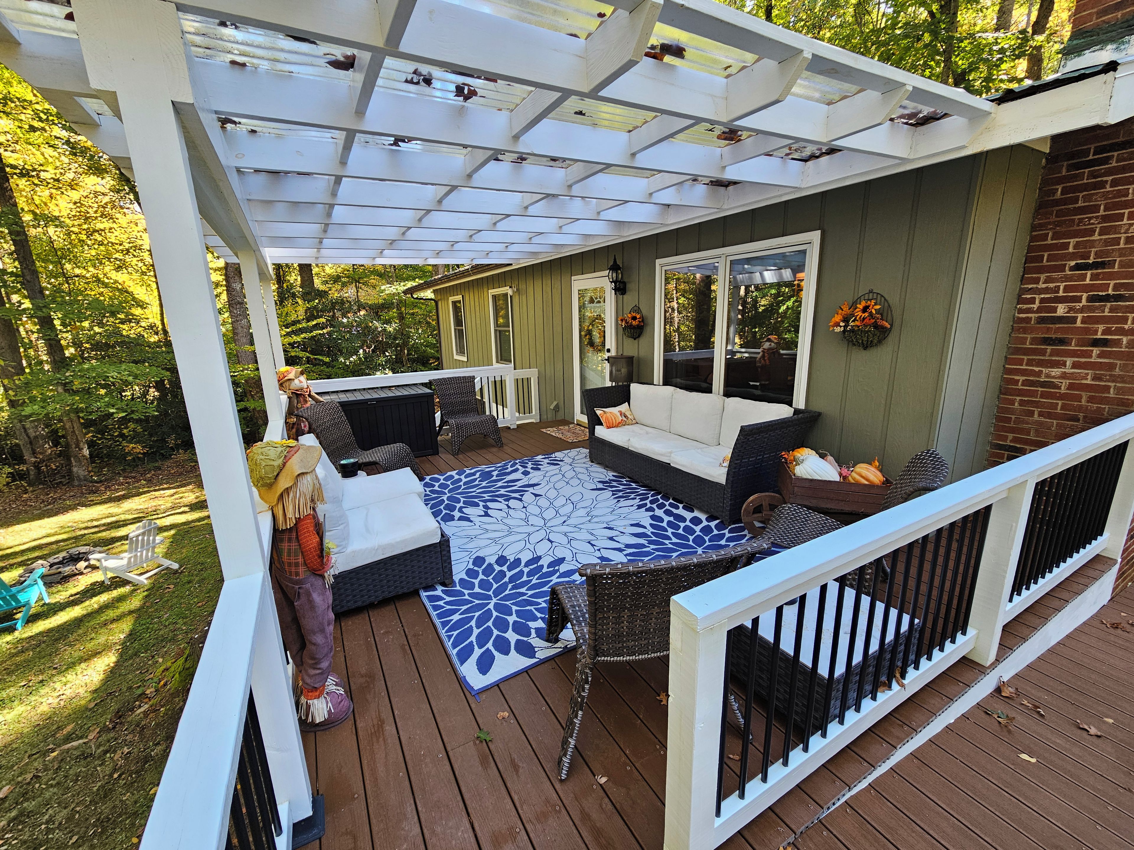 A covered deck with a sofa, chairs, and a patterned rug.