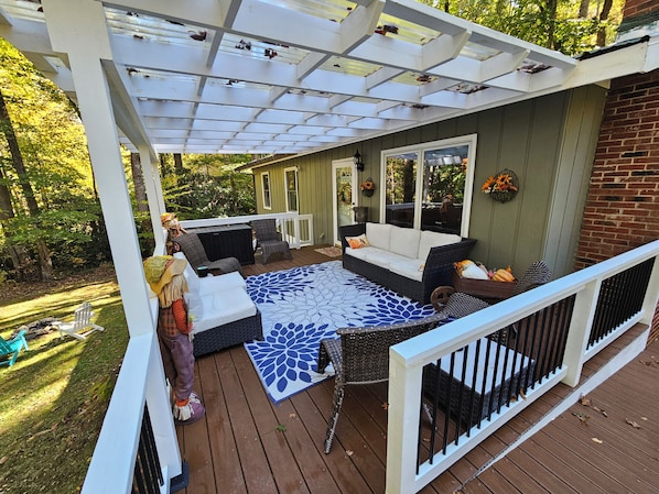 A covered deck with a sofa, chairs, and a patterned rug.