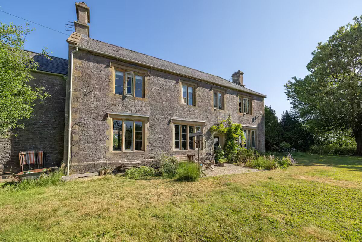 A stone house with large windows and a well-maintained lawn.