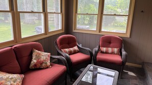 A sunroom with wicker furniture and large windows.
