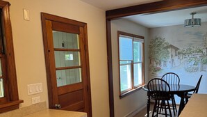 A kitchen with wooden cabinets, a dishwasher, and a dining area with chairs and a table.