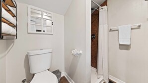 Un baño con inodoro, toallero y cortina de ducha.