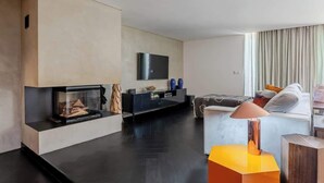 A modern living room with a fireplace, a flat-screen TV mounted on the wall, a sofa, and a coffee table. - HostWise - Modern Comfort & Shared Pool in Paredes (Vandoma)