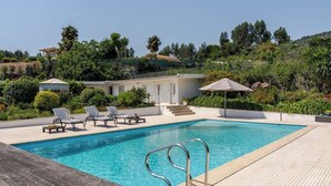 A swimming pool with lounge chairs and a wooden deck, surrounded by greenery and a hillside. - HostWise - Modern Comfort & Shared Pool in Paredes (Vandoma)