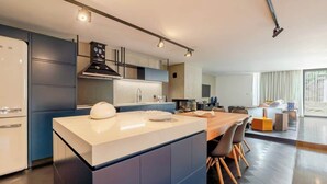 A modern kitchen with a central island, built-in appliances, and a dining area with a long table and chairs. - HostWise - Modern Comfort & Shared Pool in Paredes (Vandoma)