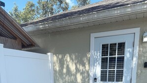 A house with a white door marked with the number 2, a welcome mat, and two metal chairs outside.