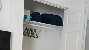 A closet with hanging clothes and a storage bin.