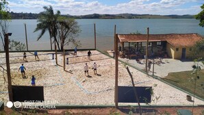 Een strandvolleybalveld met een net, een klein paviljoen en uitzicht op een meer.