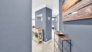 A hallway with a blue wall, a wooden console table, and a metal rack. - Poolside Villas 104 near beach sleeps 5 (Destin)
