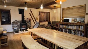 Ein gemütliches Wohnzimmer mit Holztisch, Bänken, Kamin und Bücherregal.