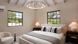 A bedroom with a large bed, two nightstands, a chair, and a ceiling fan. - Luxe Retreat With Private Pool Near Beach - The June (Dover)