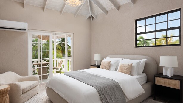 A bedroom with a bed, bedside tables, a chair, and a view of the outdoors through a sliding door. - Luxe Retreat With Private Pool Near Beach - The June (Dover)