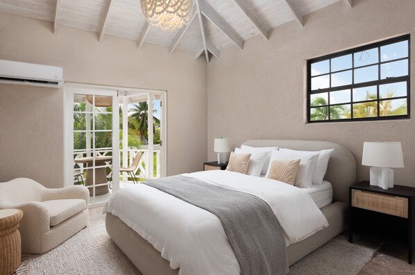 Une chambre à coucher comprenant un lit, des tables de chevet, une chaise et une vue sur l’extérieur grâce à une porte coulissante.