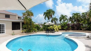 A swimming pool with a sunshade, lounge chairs, and palm trees. - Luxe Retreat With Private Pool Near Beach - The June (Dover)
