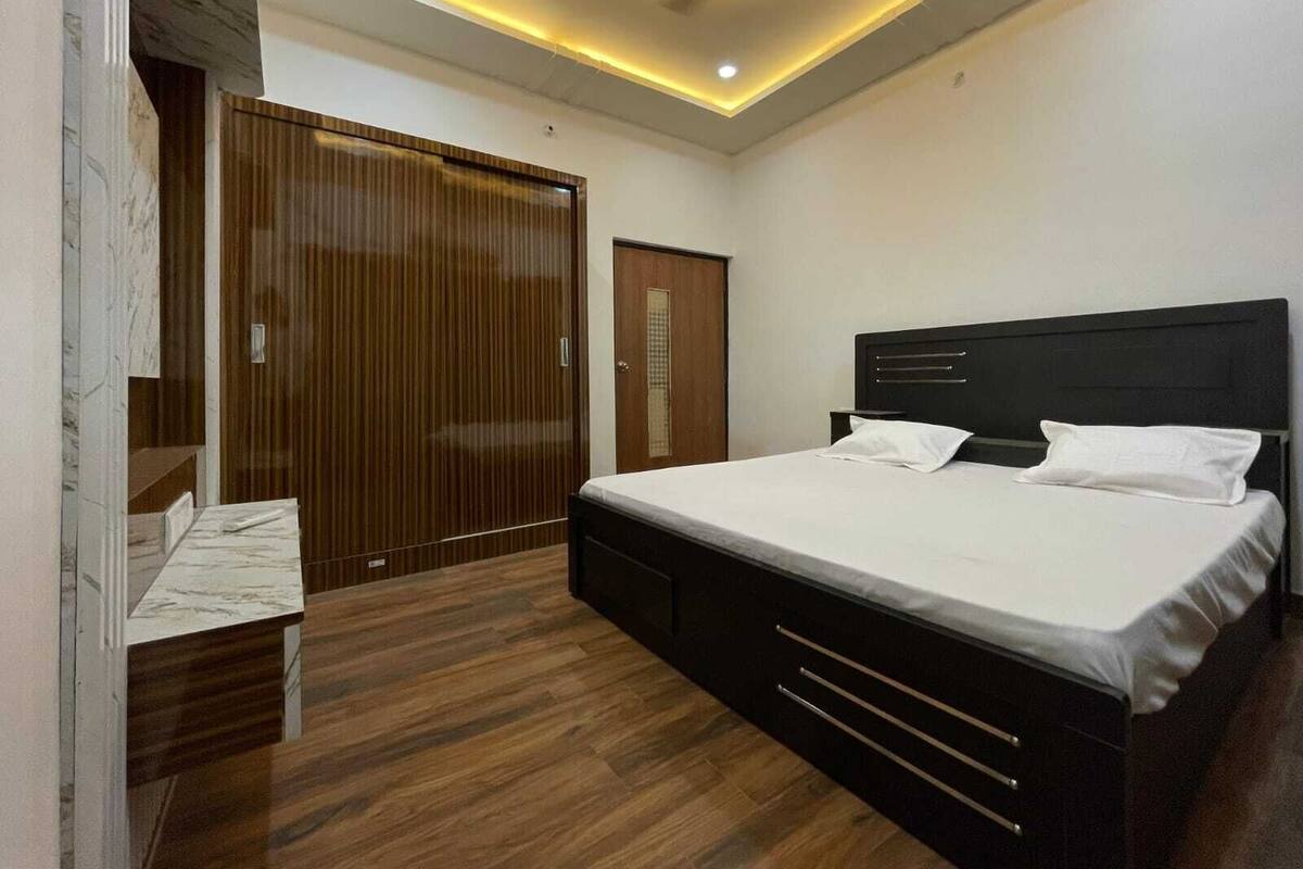 A modern bedroom with a large bed, wooden wardrobe, and a ceiling fan.