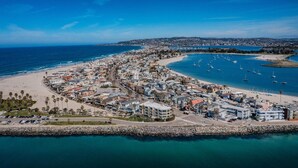 Eine Vogelperspektive einer Küstenstadt mit Strand, Marina und Wohnhäusern.