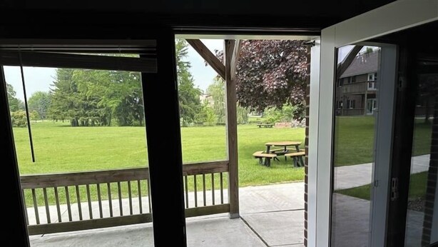 A view from a room with a sliding glass door leading to a covered patio area with a picnic table and a lawn. - Apartment Centrally Located (Plymouth)
