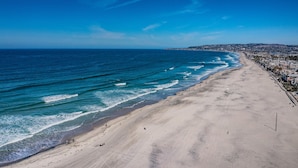 A beach with a clear view of the ocean and a distant cityscape.