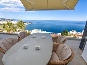 A balcony with a table and chairs, overlooking a coastal view with the sea and buildings. - Luxury Villa Facing the Sea in Cotobro (Almuñecar)