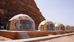 A row of dome-shaped tents with large windows, set against a rocky cliff backdrop. - Luxury Wadi Rum Camp (Wadi Rum)