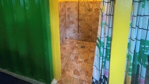 Ein Badezimmer mit Dusche, gefliesten Wänden und einer grün-gelben Farbgestaltung.
