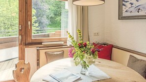 A dining area with a round table, a vase of flowers, and a painting on the wall. - Waldblick by Interhome (Seefeld in Tirol)