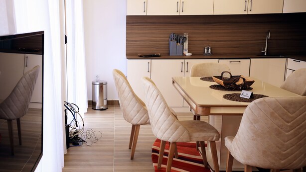 Una cocina moderna con armarios de madera, una mesa de comedor con sillas y un cubo de basura.