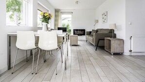 Ein modernes Wohnzimmer mit einer Couch, einem Fernseher und einem Essbereich mit Stühlen und einem Tisch.