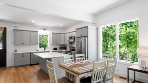 Une cuisine moderne avec des meubles gris, un îlot central et un coin repas comprenant une table et des chaises.