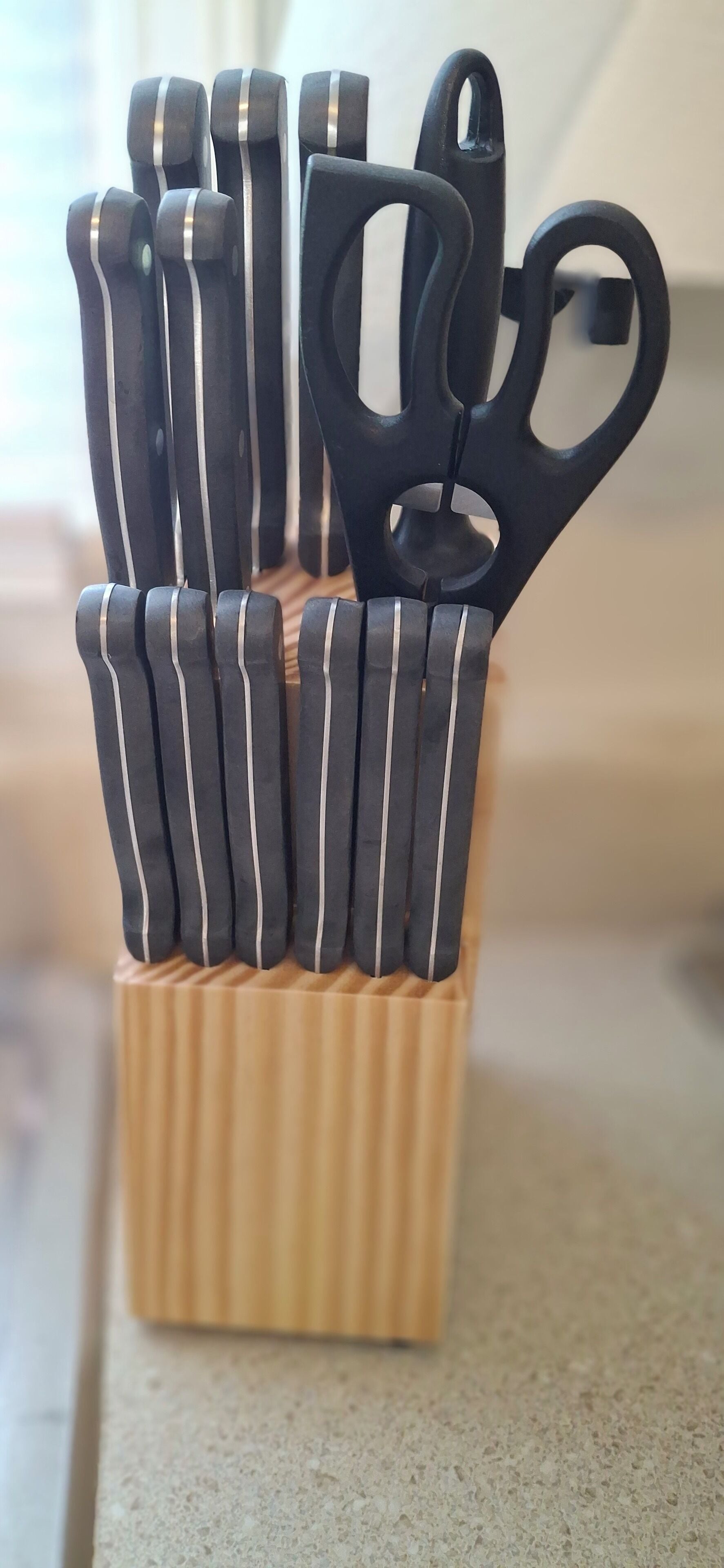 A set of black-handled scissors and knives in a wooden holder.