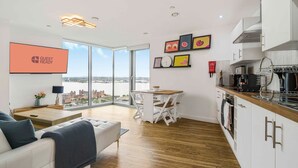 Un appartement moderne comprenant un coin repas, une cuisine et une grande fenêtre donnant sur la ville.