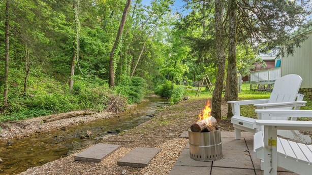 Eine Terrasse am Flussufer mit Feuerstelle und Adirondack-Stühlen.