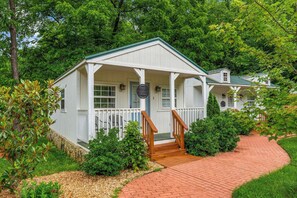 A white cottage-style building with a porch, a wooden staircase, and a brick pathway.