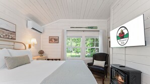 Ein Schlafzimmer mit Bett, Stuhl, Kamin und an der Wand montiertem Fernseher, der ein Logo zeigt.